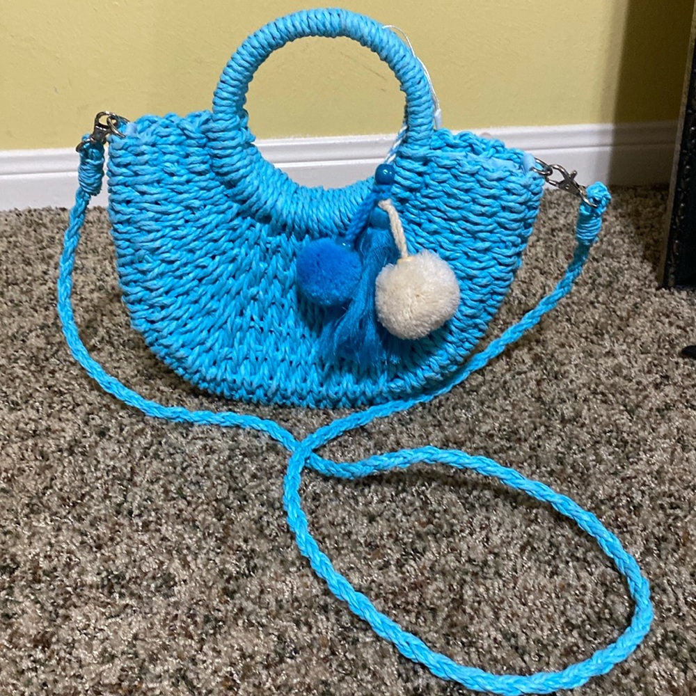 Straw crossbody in an aqua blue color with pom poms